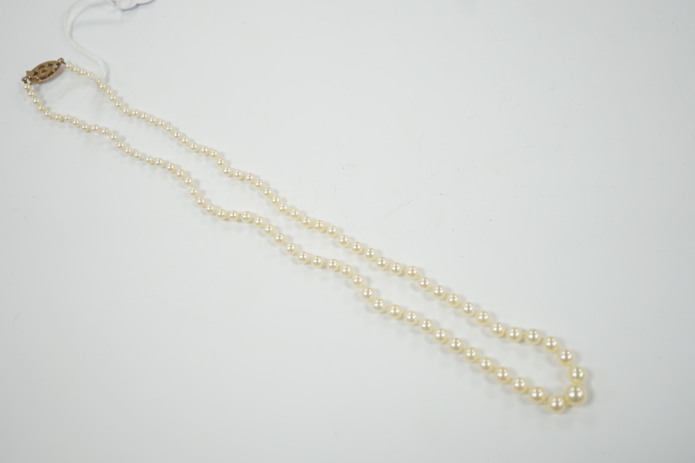 A single strand graduated cultured pearl necklace, with garnet and seed pearl set 9ct gold clasp, 52cm.